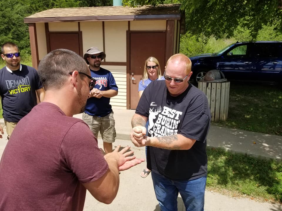 Team members enjoying a lighthearted moment during the Build-A-Boat team building challenge outdoors.