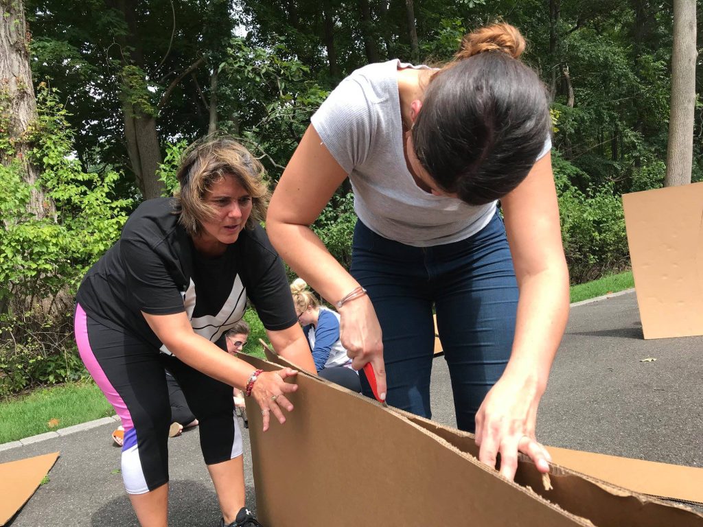 Team members cutting cardboard to construct their boat during the Build-A-Boat team building activity.