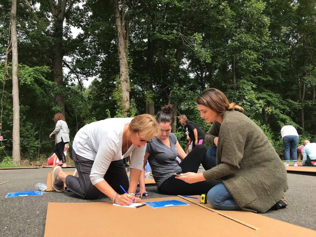 A group of participants collaborating on boat blueprints during the Build-A-Boat team building challenge.