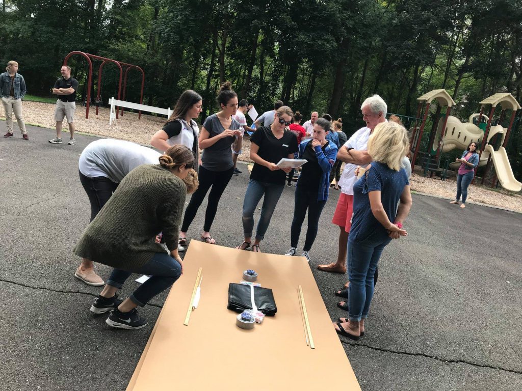 Team brainstorming and planning their cardboard boat design during a Build-A-Boat team building challenge.