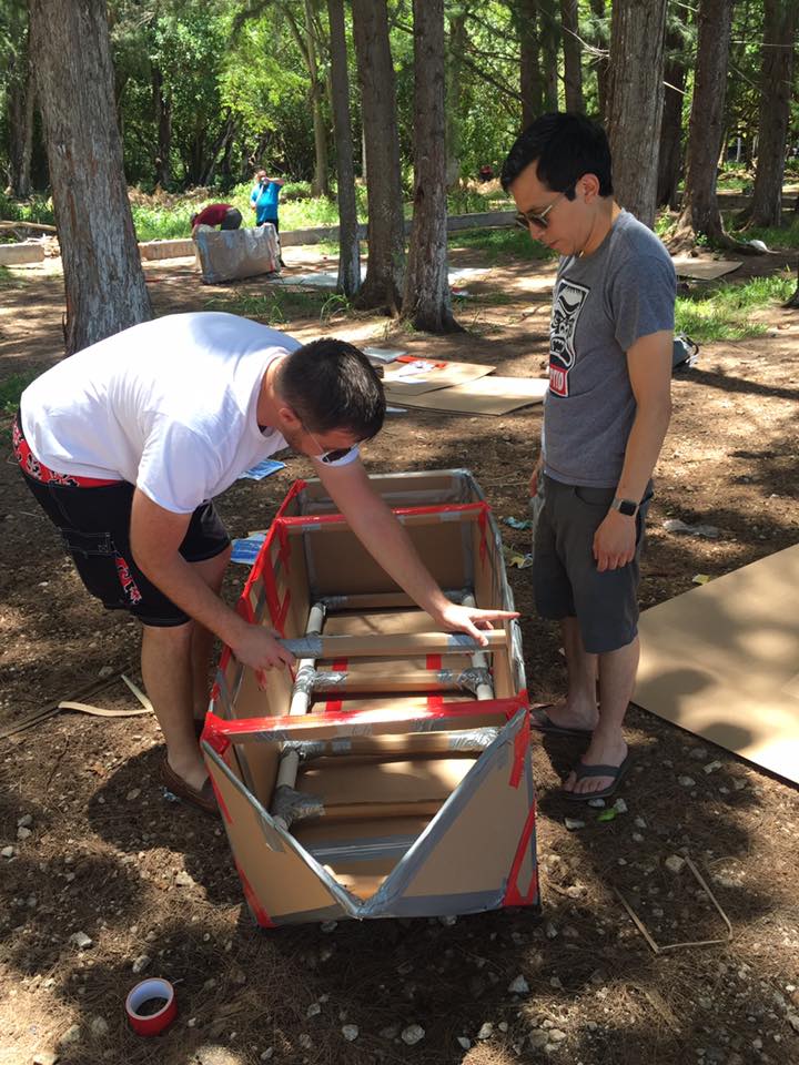 Two participants assembling the structure of a cardboard boat during the Build-A-Boat team building activity.