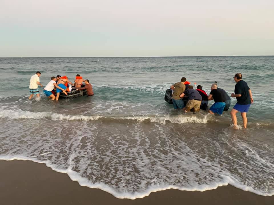 Participants launching their cardboard boats into the ocean during the Build-A-Boat team building challenge.