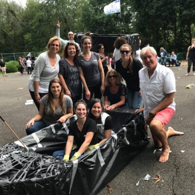 Team posing with their completed cardboard boat during the Build-A-Boat team building challenge.