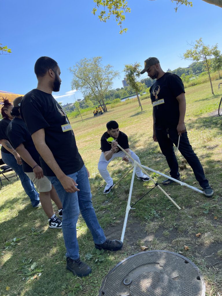 Participants outdoors collaborating on building a catapult during the Catapult to Success team building activity, showcasing teamwork, problem-solving, and creativity in a natural setting.