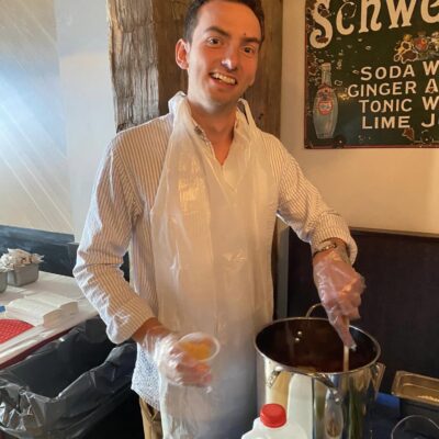 Smiling participant stirring a pot during the Wicked Good Chowda Cook-Off team building event.