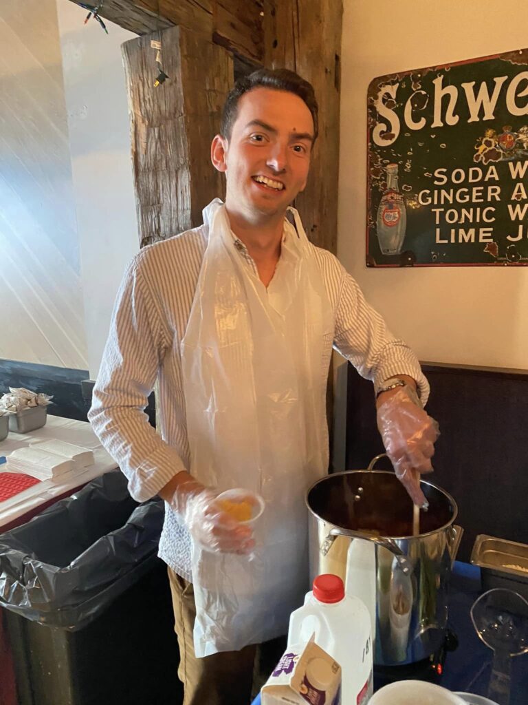 Smiling participant stirring a pot during the Wicked Good Chowda Cook-Off team building event.