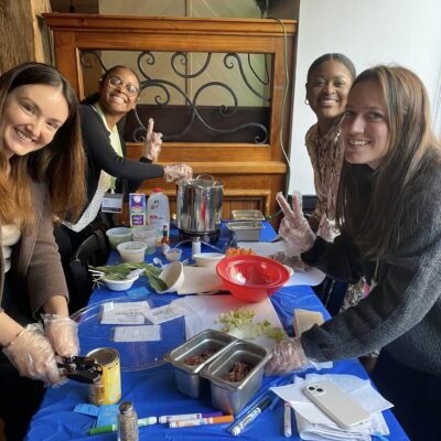 Group of participants smiling while preparing ingredients for the Wicked Good Chowda Cook-Off team building event.