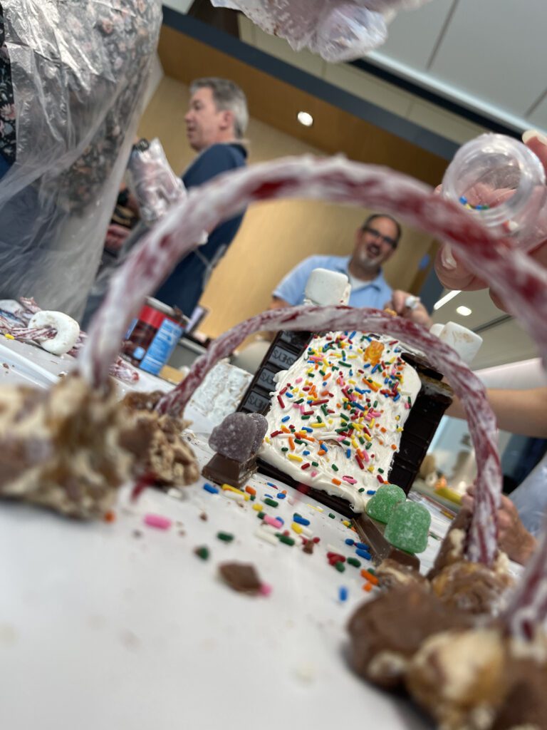 A creative chocolate bridge decorated with sprinkles, candy, and licorice arches, built during The Chocolate Challenge team building event. Participants focus on collaboration and edible engineering.