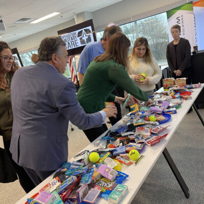 Participants gather supplies for care packages during an Operation Military Care team building event, preparing gifts for U.S. military personnel overseas.