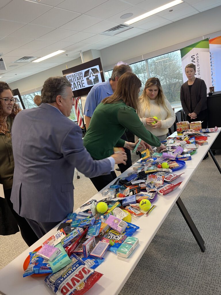 Participants gather supplies for care packages during an Operation Military Care team building event, preparing gifts for U.S. military personnel overseas.