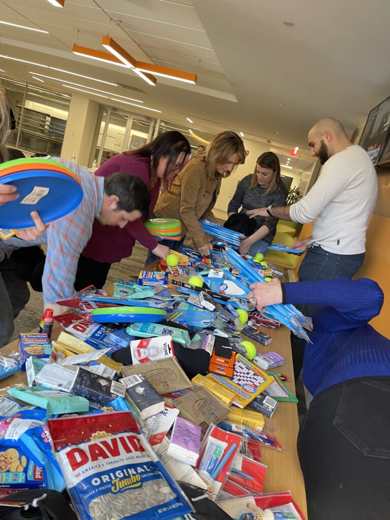 Team members packing items for care packages during an Operation Military Care team building event, creating impactful gifts for U.S. military personnel.