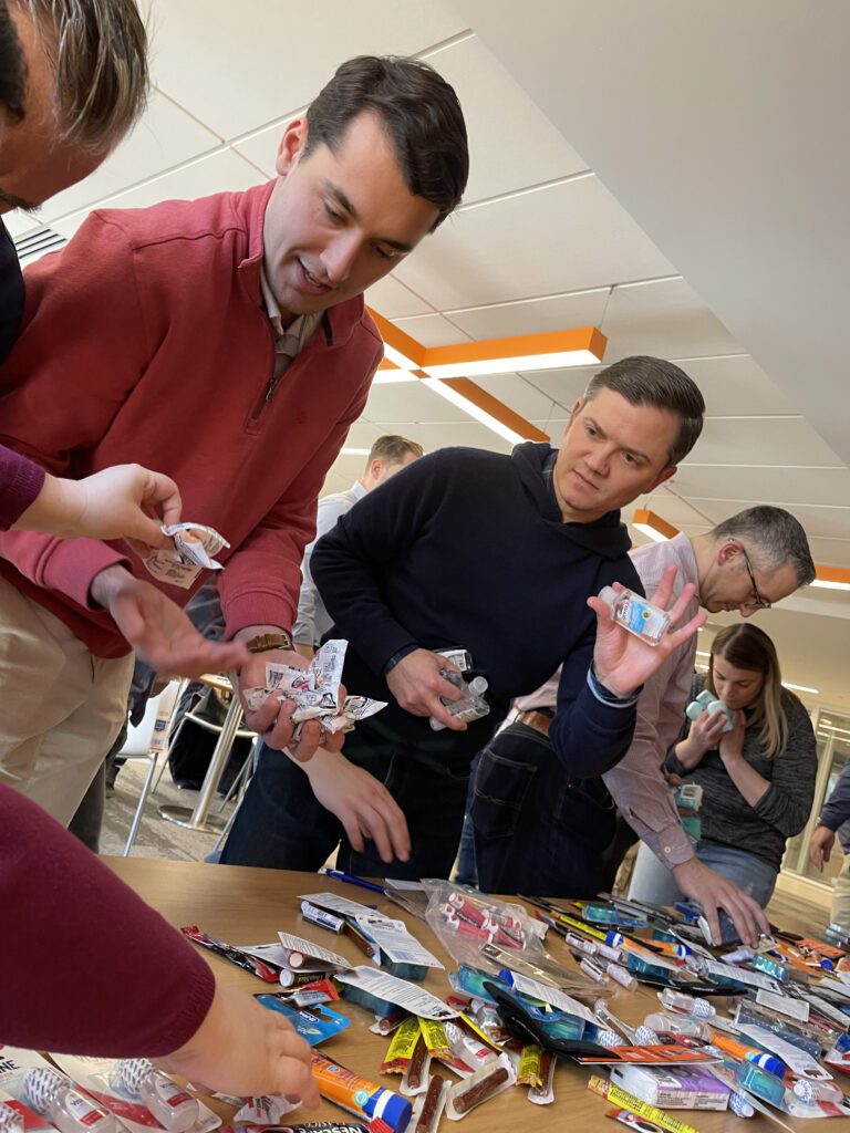 Employees working together to collect and pack items for military care packages during a team building event.