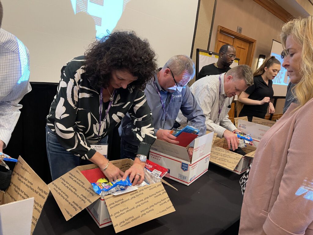 Participants packing care packages with essentials for military personnel, contributing to a rewarding team building experience.