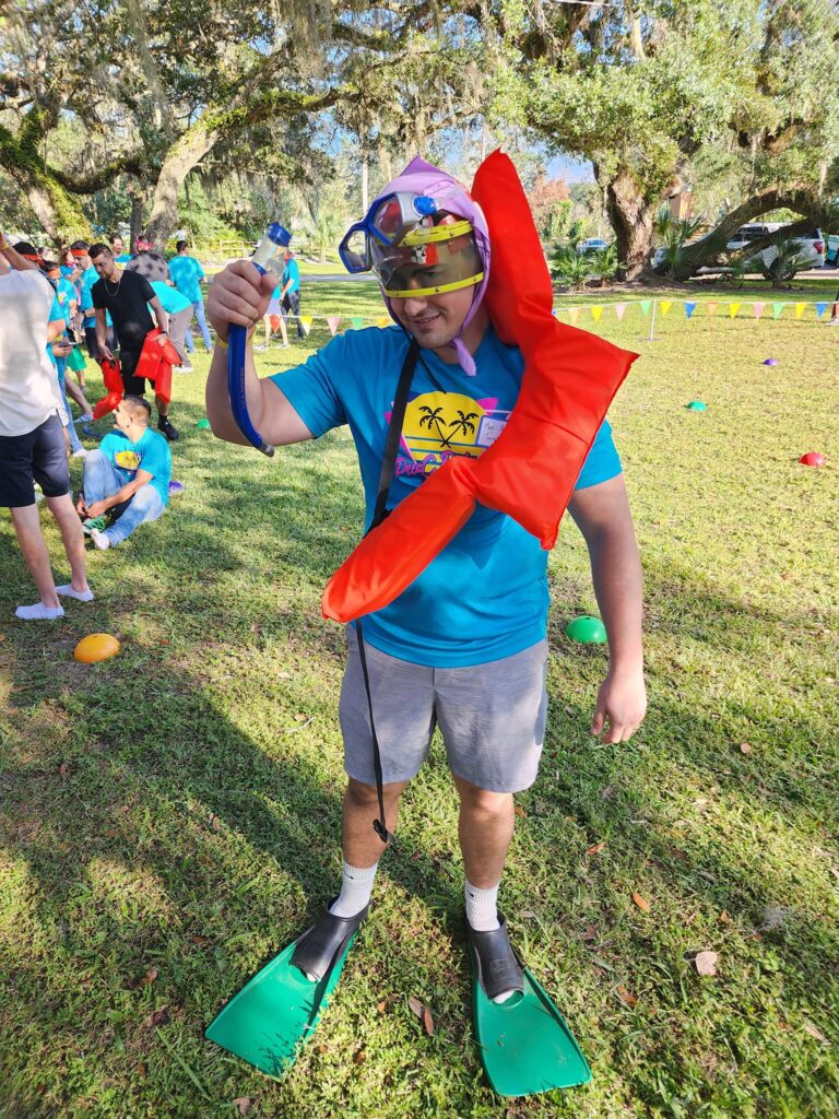 A participant dressed in fun, wacky gear during the Outrageous Games team building event, ready to take on a unique challenge in flippers, a life vest, and goggles.