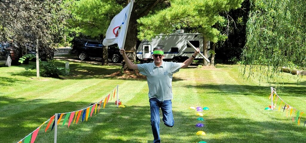 Participant in Outrageous Games team building event celebrates crossing the finish line during a fun, non-athletic relay challenge.