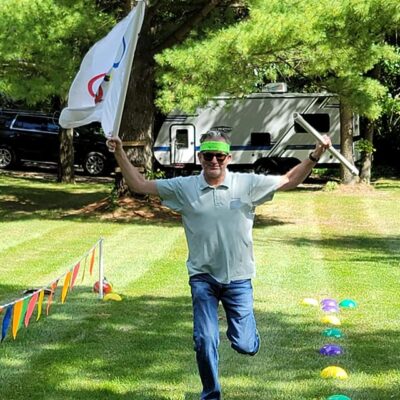 Participant in Outrageous Games team building event celebrates crossing the finish line during a fun, non-athletic relay challenge.