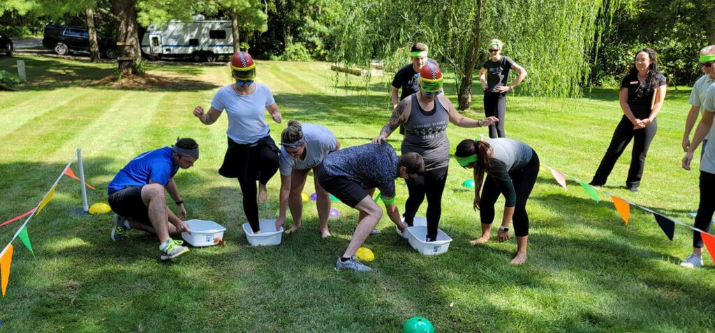 Teams tackling a wacky challenge in the Outrageous Games team building event, fostering collaboration and communication.