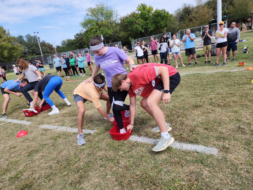 Participants work together to navigate a relay race during the Outrageous Games team building event, encouraging teamwork and problem-solving.