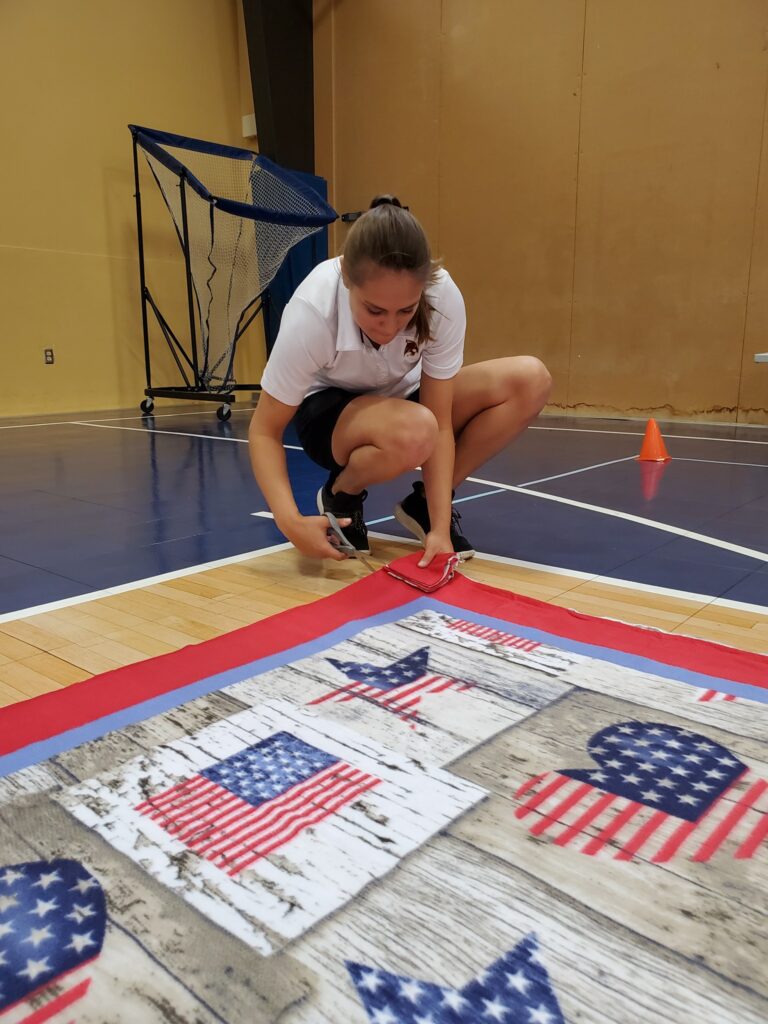 Team member diligently cuts fabric to assemble a fleece blanket during The Big Give charity team building event.