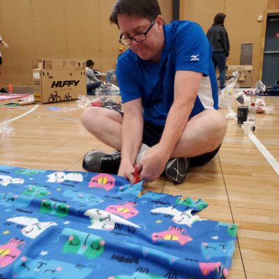 Team member diligently cuts fabric to assemble a fleece blanket during The Big Give charity team building event.