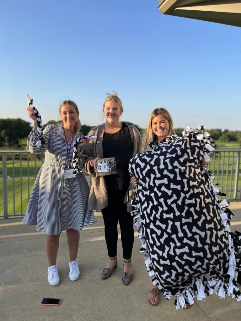 Team members proudly present their completed dog bed, toy, and treats after a successful Paws For A Cause team building event, benefiting local animal shelters.