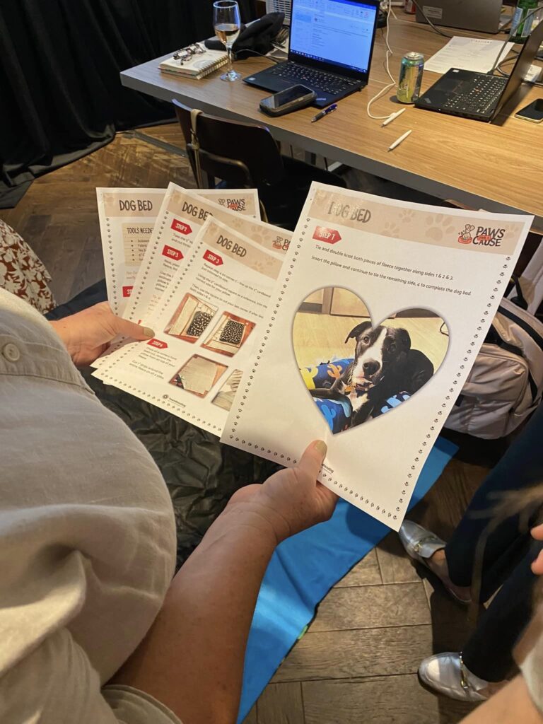 A participant at the Paws For A Cause team building event reviews step-by-step instructions for creating dog beds to be donated to local animal shelters, ensuring the project meets all requirements.