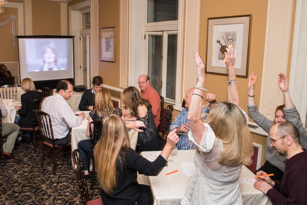 Excited participants raising their hands during a lively Wild Card Team Building Bingo event