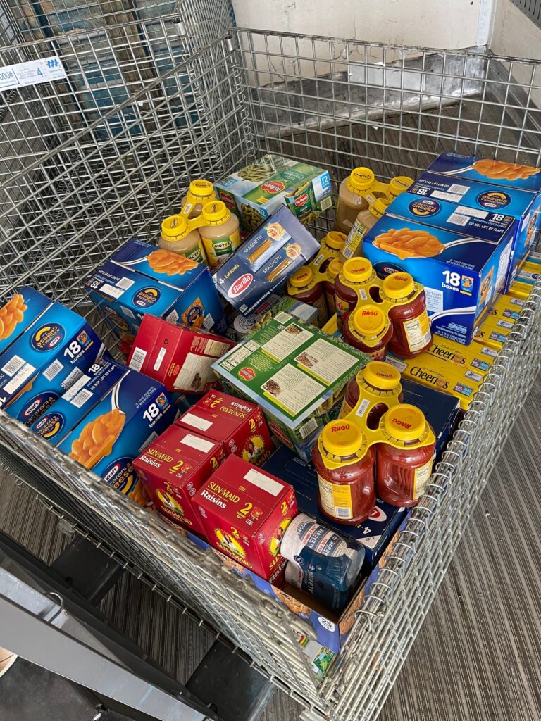 Cart filled with groceries and non-perishable items collected by a team during the Foodbank Showdown event, ready to be donated to support local families in need.