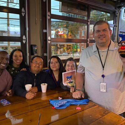 A cheerful group of colleagues enjoying the Pub Crawl Scavenger Hunt, proudly showing off their creative achievements as part of the fun and camaraderie building event.