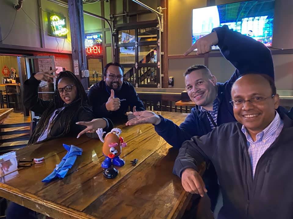 Team posing with Mr. Potato Head during a lively Pub Crawl Scavenger Hunt, fostering camaraderie and shared adventures in a relaxed pub setting.