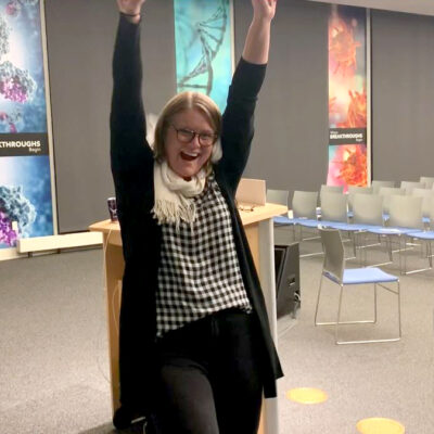 A participant celebrates with raised arms after successfully breaking a board during a team building activity focused on overcoming obstacles.