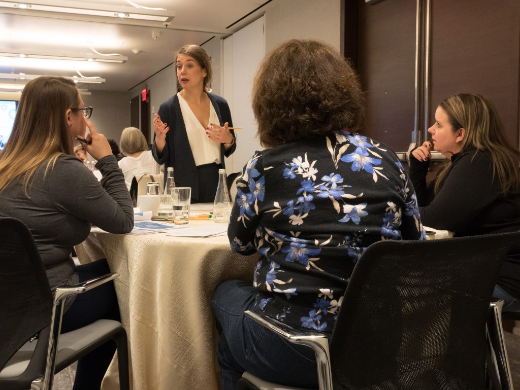 A facilitator leading a discussion with a small group of participants during the Team and Leadership DNA workshop, encouraging collaboration and sharing insights.