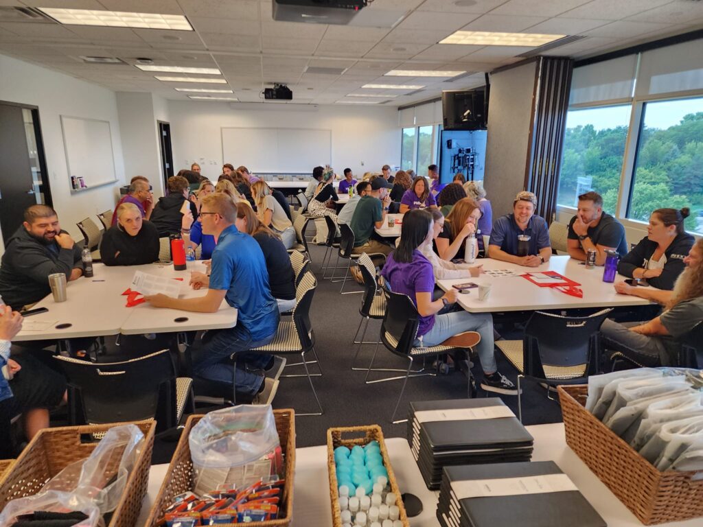 Teams gathered at a corporate team building session for Hopefull Handbags Global, preparing to pack essential items into handbags for women survivors of domestic abuse.