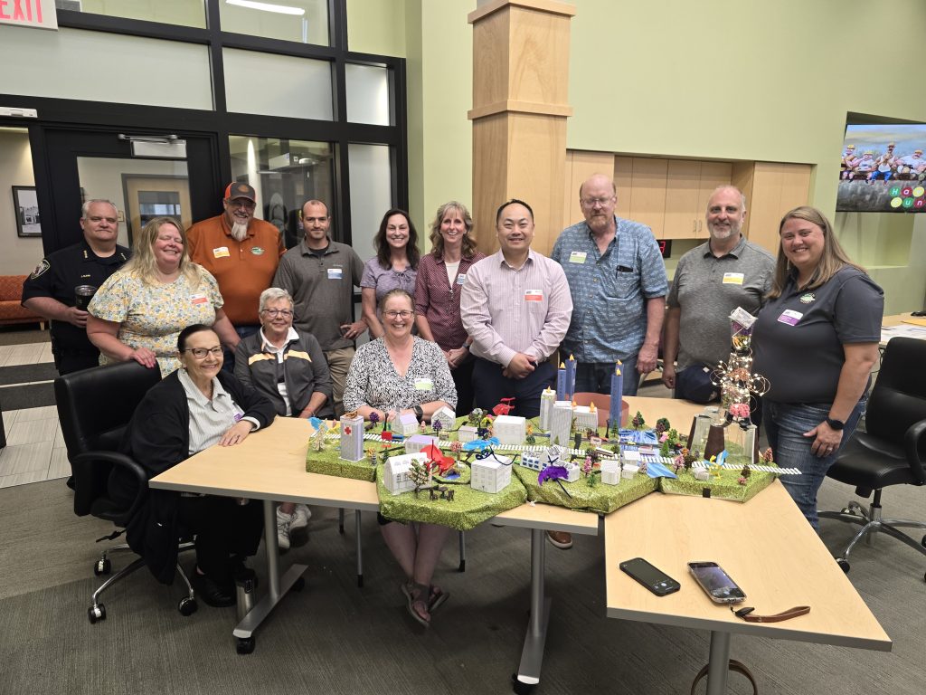 Group photo of participants proudly showcasing their completed miniature city model at the City Build team building event.