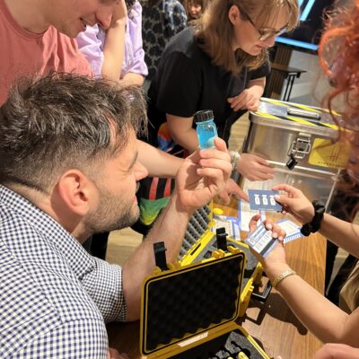 Team members collaborating during the 'Atmosphere' team building event, examining a vial as part of a puzzle.