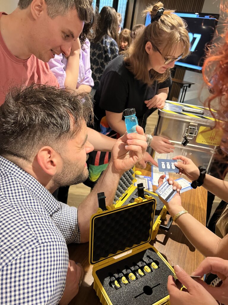 Team members collaborating during the 'Atmosphere' team building event, examining a vial as part of a puzzle.