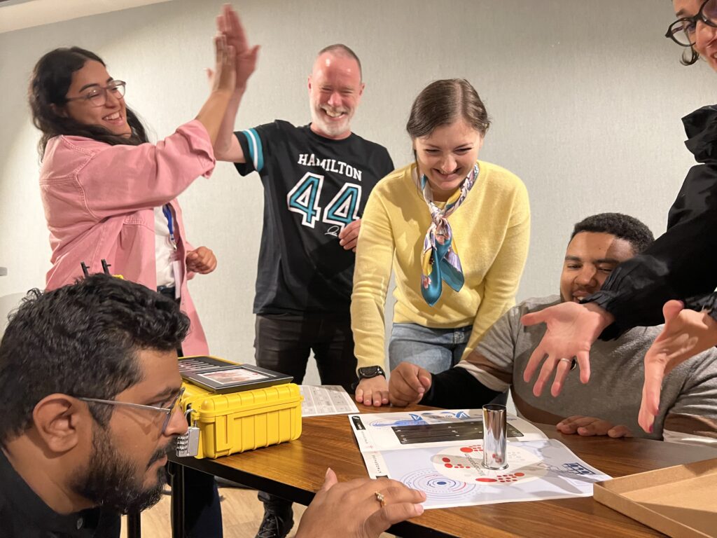 Team celebrating a breakthrough while solving puzzles during the 'Atmosphere' team building event.