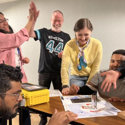 Team celebrating a breakthrough while solving puzzles during the 'Atmosphere' team building event.