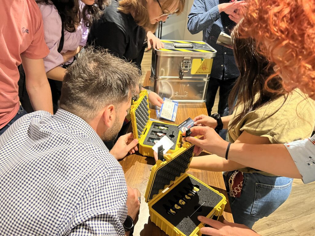 Participants carefully analyzing clues from locked containers during the 'Atmosphere' team building challenge, working together to crack the code.