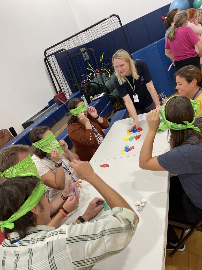 A team collaborating on a challenge during the Integrity team building event, with participants wearing blindfolds and communicating to solve tasks.