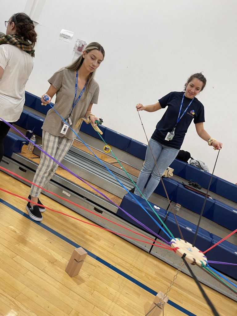 Participants working together in the Integrity team building event, using ropes to carefully balance wooden blocks as part of a collaboration challenge.