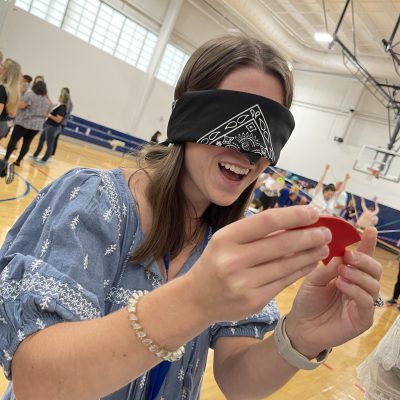 A participant blindfolded and smiling while completing a challenge in the Integrity team building event, focused on teamwork and communication.