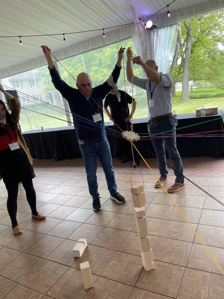 Team members working together in the Integrity team building event, using ropes and teamwork to balance wooden blocks in a collaborative challenge.