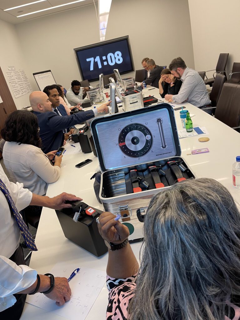 Teams focused on unlocking clues and solving puzzles during a Beat The Box team building event, with a ticking clock adding pressure to their collaboration and problem-solving efforts.