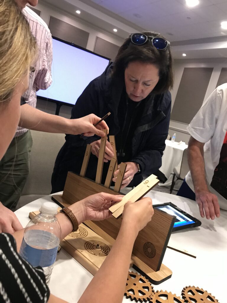 Team members collaborate on a wooden puzzle during the 'Escape The Maze' team building event, focusing on strategy and communication skills.