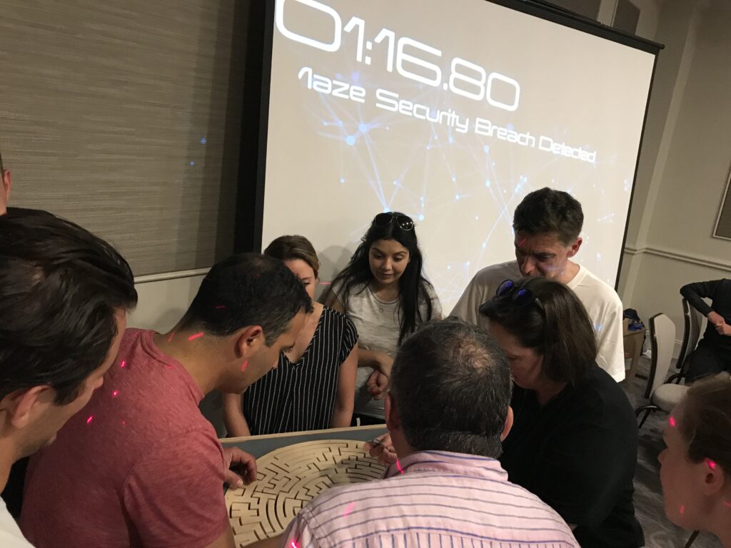 Participants work together to solve a maze puzzle under a countdown timer display during the 'Escape The Maze' team building event, enhancing their problem-solving and communication skills under time pressure.