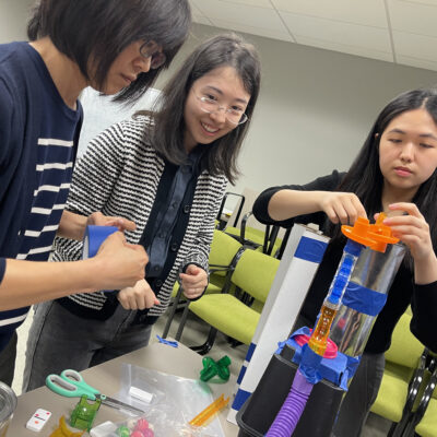 Team members focus on assembling a complex contraption during the Domino Effect team building event, working together to foster creativity and problem-solving.