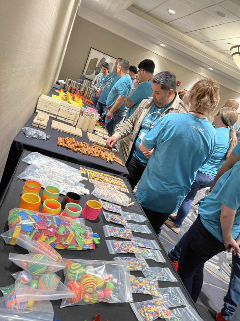 Participants selecting colorful supplies and materials for a team building Domino Effect activity, where teams construct intricate machines.