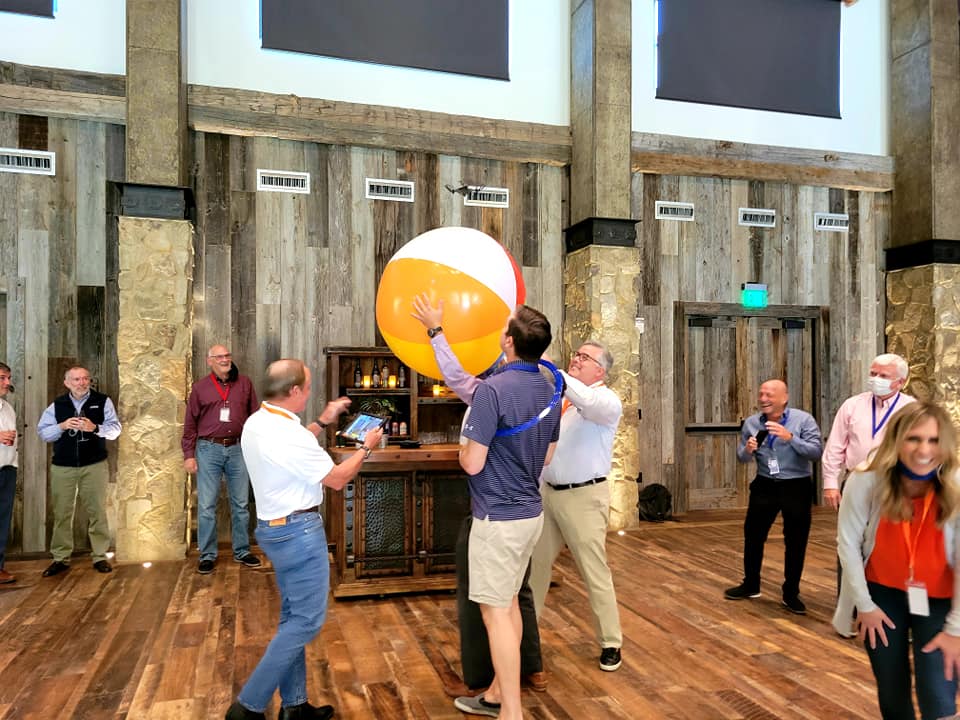 Participants work together to keep a giant beach ball in the air during a lively team building activity, fostering collaboration and fun.