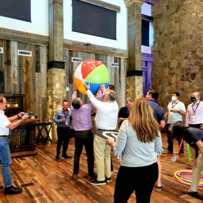 Team members collaborate to maneuver a large beach ball during the Game of Drones team building event, combining coordination and communication in a fun and dynamic environment.